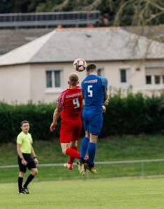 Two soccer players fiercely competing for a header during a match in France.